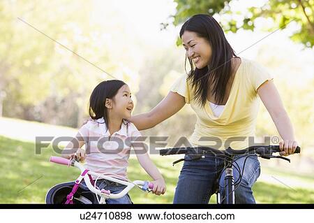 Woman and young girl on bikes outdoors smiling View Large Photo Image Stock Photo - Woman and young girl on bikes outdoors smiling. Fotosearch