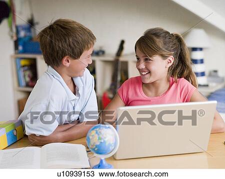 Stock Image - Boy And Girl Doing Their Homework On A Laptop. Fotosearch
