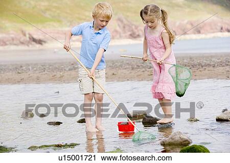 Brother and sister at beach with nets and pail View Large Photo Image Stock Image - Brother and sister at beach with nets and pail. Fotosearch