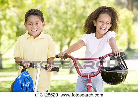 Brother and sister outdoors with scooter and bicycle smiling View Large Photo Image Stock Photo - Brother and sister outdoors with scooter and bicycle smiling. Fotosearch