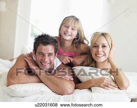 Family lying in bed smiling View Large Photo Image Stock Photo - Family lying in bed smiling. Fotosearch