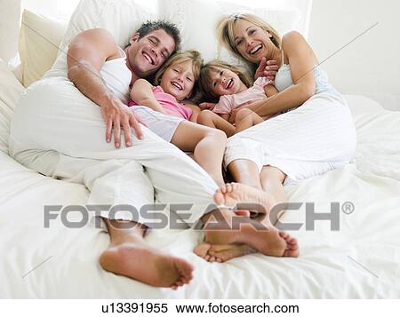Family lying in bed smiling View Large Photo Image Stock Photography - Family lying in bed smiling. Fotosearch