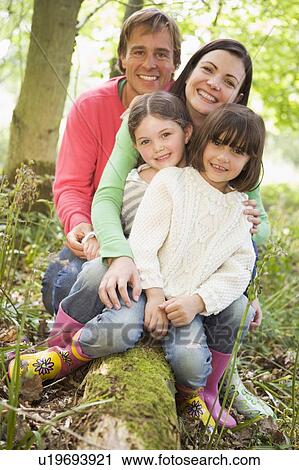 Family outdoors in woods sitting on log smiling View Large Photo Image Stock Image - Family outdoors in woods sitting on log smiling. Fotosearch