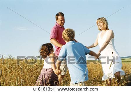 Stock Image - Family playing outdoors smiling. Fotosearch
