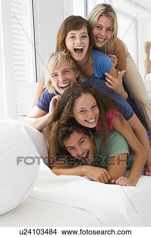 Picture - Five people in living room piled up smiling. Fotosearch