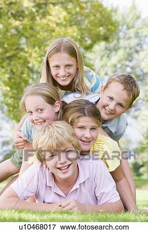 Five young friends piled on each other outdoors smiling View Large Photo Image Stock Photo - Five young friends piled on each other outdoors smiling. Fotosearch