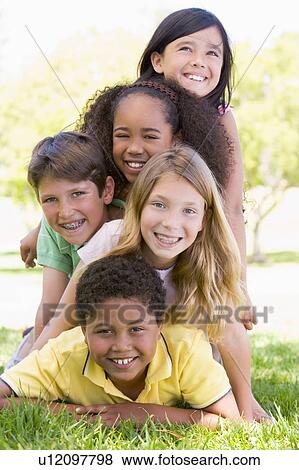 Stock Photo - Five young friends piled up on top of each other outdoors smiling. Fotosearch