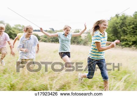 Stock Photograph - Five young friends running in a field smiling. Fotosearch