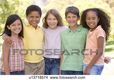 Picture - Five young friends standing outdoors smiling. Fotosearch