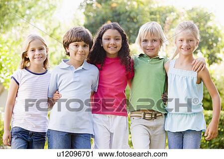 Stock Image - Five young friends standing outdoors smiling. Fotosearch