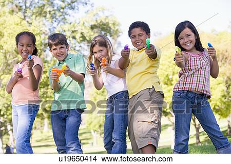 Picture - Five young friends with water guns outdoors smiling. Fotosearch