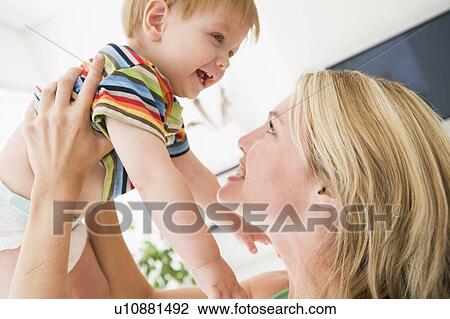 Mother in living room holding baby smiling View Large Photo Image Stock Image - Mother in living room holding baby smiling. Fotosearch