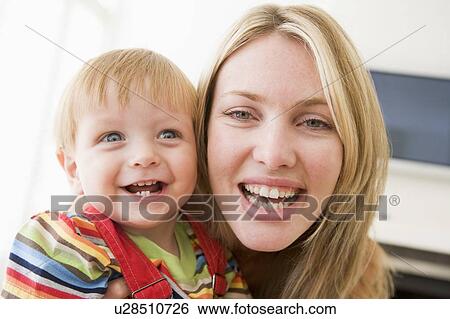 Mother in living room holding baby smiling View Large Photo Image Stock Photograph - Mother in living room holding baby smiling. Fotosearch