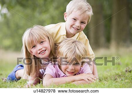Stock Photo - Three young children playing outdoors smiling. Fotosearch