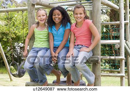 Stock Photo - Three young girl friends at a playground smiling. Fotosearch