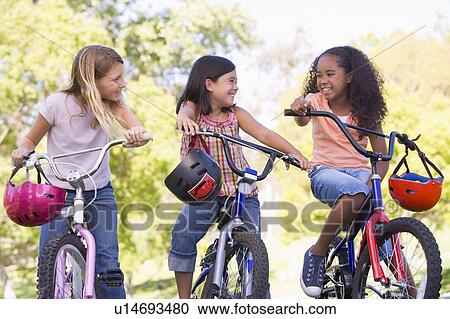 Three young girl friends outdoors on bicycles smiling View Large Photo Image Stock Image - Three young girl friends outdoors on bicycles smiling. Fotosearch