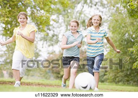 Stock Photo - Three young girl friends playing soccer. Fotosearch