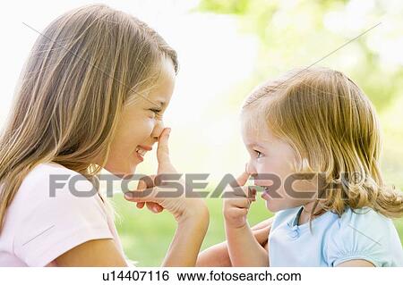 Stock Photograph - Two sisters playing outdoors and smiling. Fotosearch