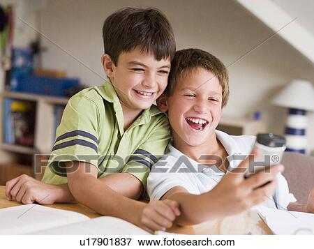 Two Young Boys Distracted From Their Homework, Playing With A Cellphone View Large Photo Image Stock Photo - Two Young Boys Distracted From Their Homework, Playing With A Cellphone. Fotosearch