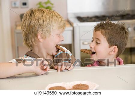 Two young boys in kitchen eating cookies smiling View Large Photo Image Stock Image - Two young boys in kitchen eating cookies smiling. Fotosearch