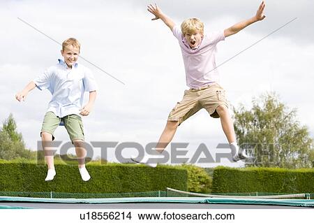 Two young boys jumping on trampoline smiling View Large Photo Image Picture - Two young boys jumping on trampoline smiling. Fotosearch