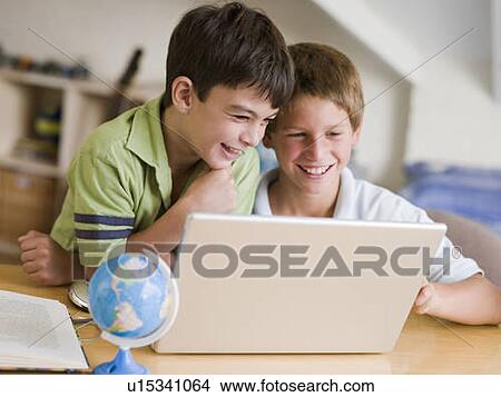 Picture - Two Young Boys Using A Laptop At Home. Fotosearch