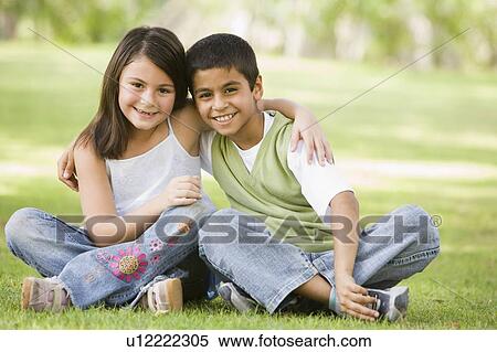 Stock Photography - Two young children outdoors in park bonding and smiling (selective focus). Fotosearch