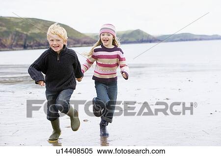 Two young children running on beach holding hands smiling View Large Photo Image Stock Photography - Two young children running on beach holding hands smiling. Fotosearch