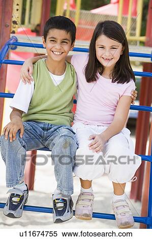 Two young children sitting on playground structure smiling (selective focus) View Large Photo Image Stock Photography - Two young children sitting on playground structure smiling (selective focus). Fotosearch