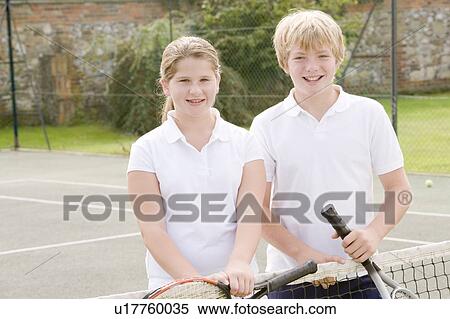 Two young friends with rackets on tennis court smiling View Large Photo Image Stock Photography - Two young friends with rackets on tennis court smiling. Fotosearch