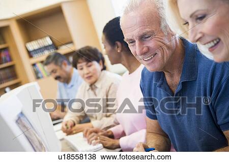 Stock Photo - Five people at computer terminals in library (depth of field). Fotosearch