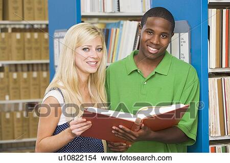 Picture - Man and woman in library holding book (depth of field). Fotosearch