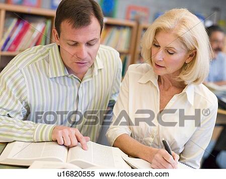 Man and woman in library looking over a book (selective focus) View Large Photo Image Stock Photography - Man and woman in library looking over a book (selective focus). Fotosearch