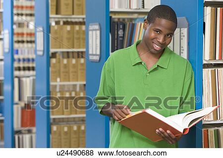 Stock Photo - Man in library holding book (depth of field). Fotosearch