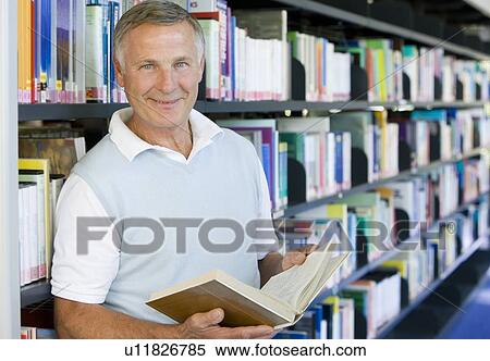 Man in library holding book (depth of field) View Large Photo Image Stock Photography - Man in library holding book (depth of field). Fotosearch
