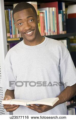 Man in library holding book View Large Photo Image Stock Photograph - Man in library holding book. Fotosearch