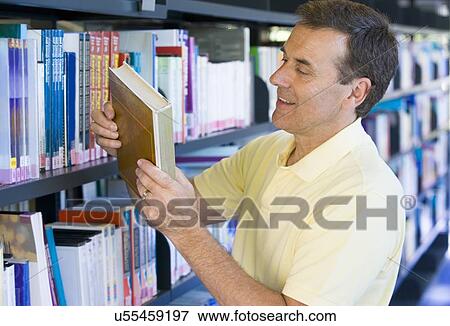 Stock Photo - Man in library looking at book (depth of field). Fotosearch