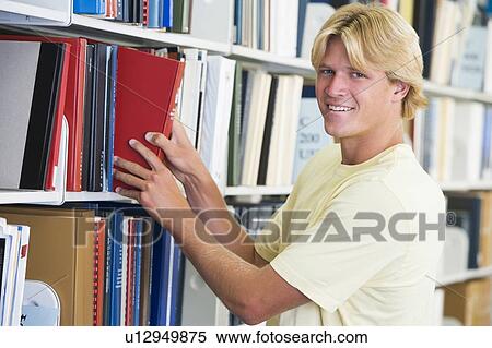 Stock Photography - Man in library pulling book off a shelf (depth of field). Fotosearch