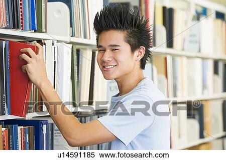 Stock Photography - Man in library pulling book off a shelf (depth of field). Fotosearch