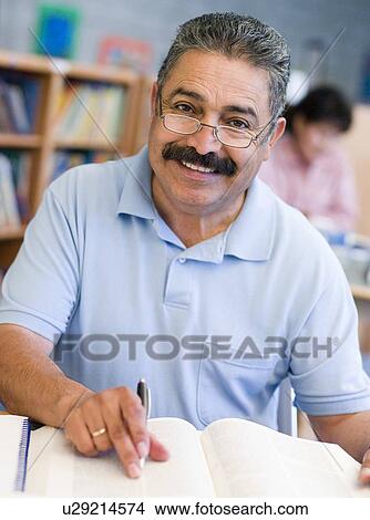 Man sitting in library with a book and notepad (selective focus) View Large Photo Image Picture - Man sitting in library with a book and notepad (selective focus). Fotosearch
