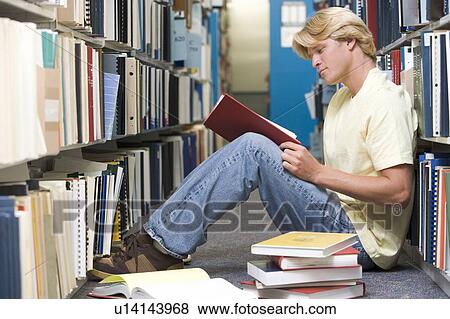 Stock Photo - Man sitting on floor in library reading book. Fotosearch