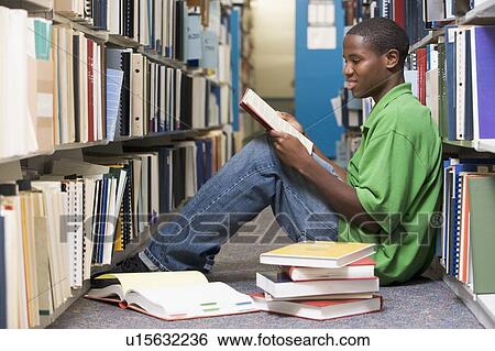Man sitting on floor in library reading book View Large Photo Image Stock Photograph - Man sitting on floor in library reading book. Fotosearch