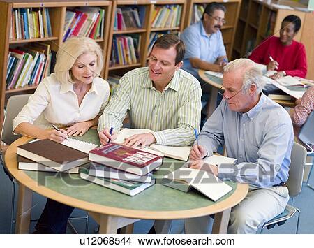 Picture - Three people in library with notepads (selective focus). Fotosearch