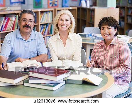 Three people sitting in library with books and notepads (selective focus) View Large Photo Image Stock Photograph - Three people sitting in library with books and notepads (selective focus). Fotosearch