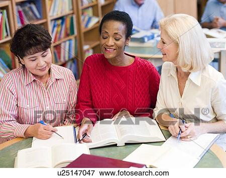 Three women sitting in library with books and notepads (selective focus) View Large Photo Image Stock Photo - Three women sitting in library with books and notepads (selective focus). Fotosearch