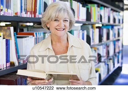 Woman in library holding book (depth of field) View Large Photo Image Stock Image - Woman in library holding book (depth of field). Fotosearch