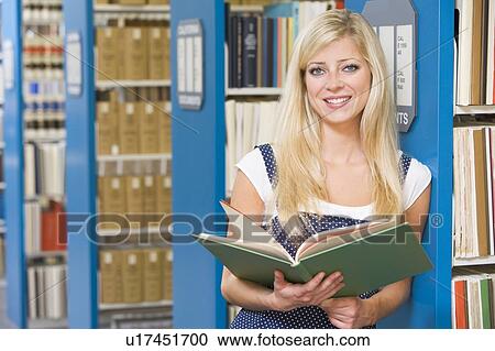 Woman in library holding book (depth of field) View Large Photo Image Stock Image - Woman in library holding book (depth of field). Fotosearch