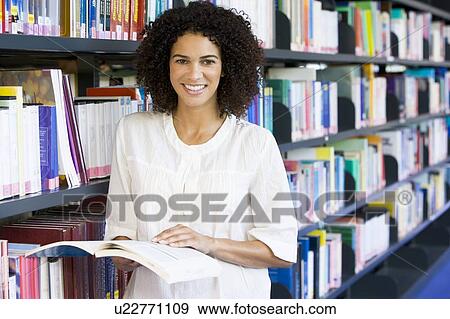 Woman in library holding book (depth of field) View Large Photo Image Stock Photo - Woman in library holding book (depth of field). Fotosearch