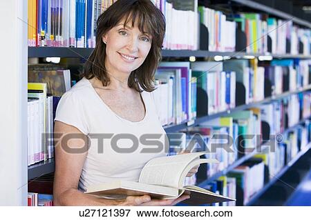 Stock Photo - Woman in library holding book (depth of field). Fotosearch
