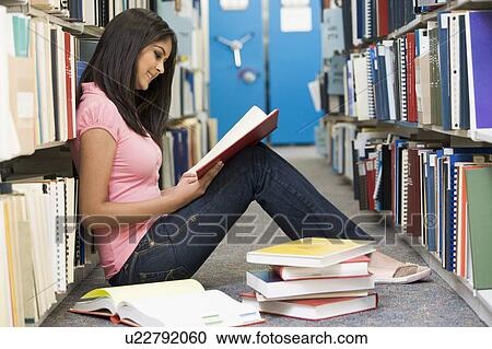 Woman sitting on floor in library reading book View Large Photo Image Stock Image - Woman sitting on floor in library reading book. Fotosearch